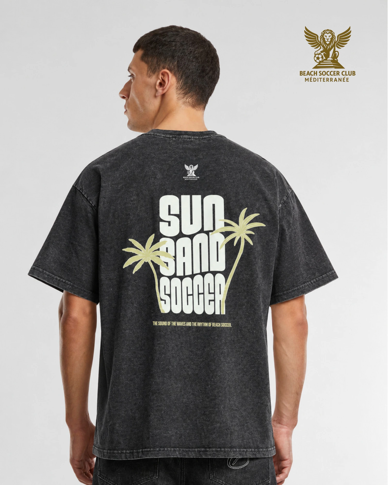Back view of the BSCM CAPSULE washed charcoal-black T-shirt with cream palm-tree artwork and the BSCM crest.