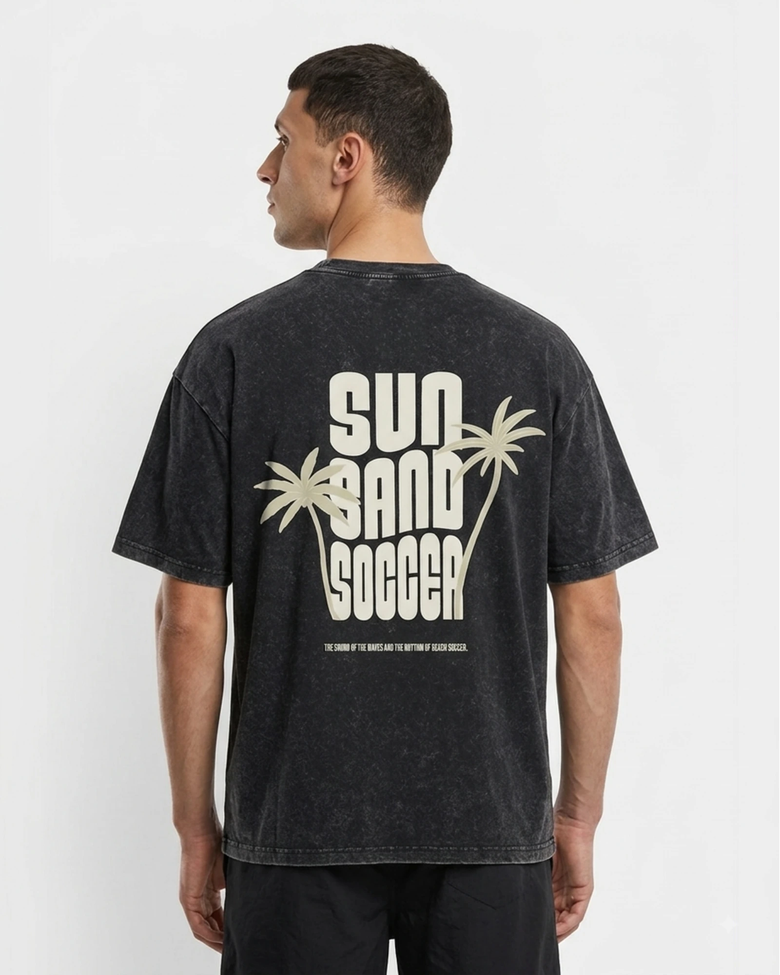 Back view of the SUN SAND SOCCER washed charcoal-black T-shirt with cream palm-tree artwork.